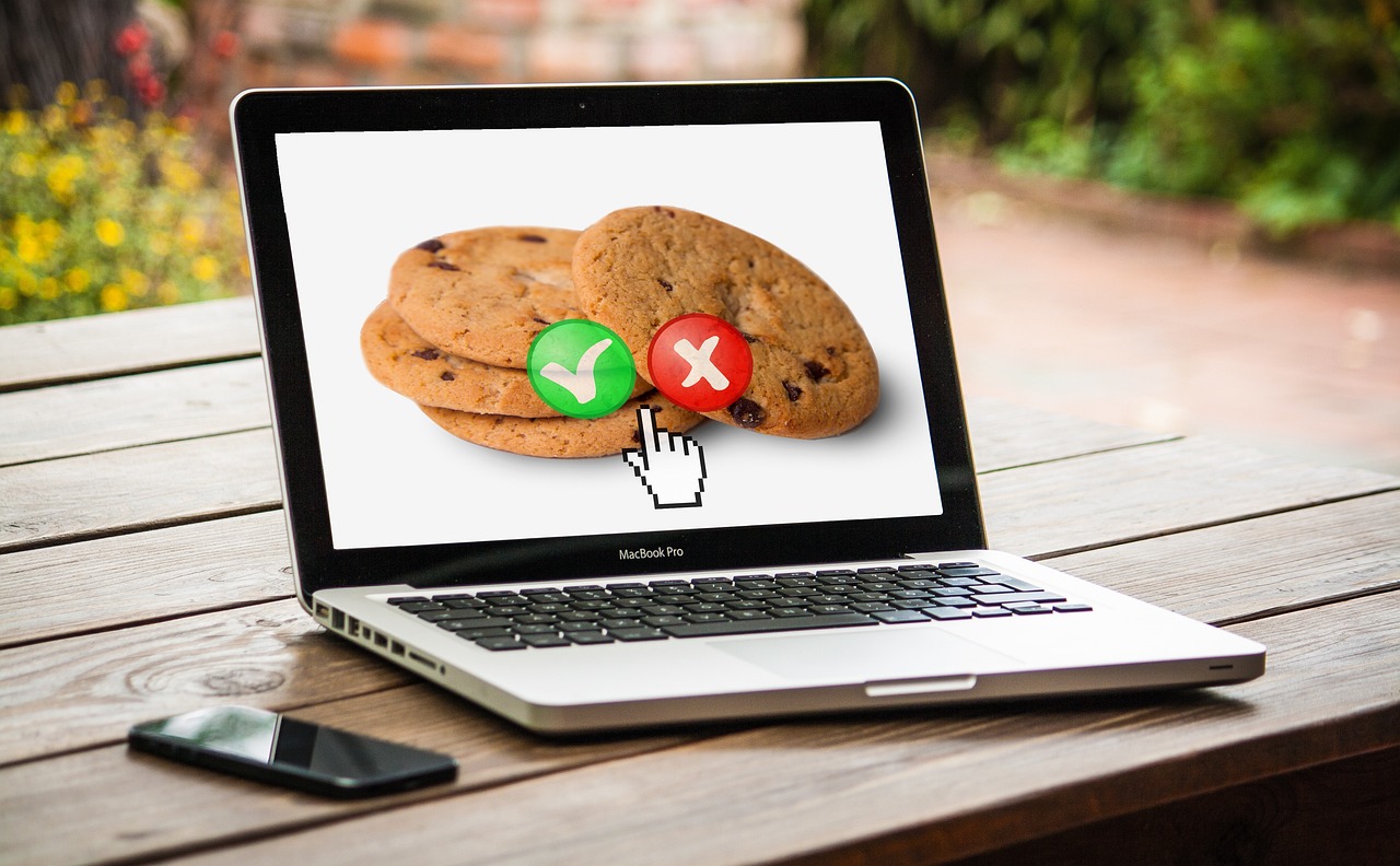 A laptop showing chocolate-chip cookies with green accept and red reject buttons - a visual play on web cookie consent. Blocking ad and tracker requests shrinks how much of your browsing is profiled.