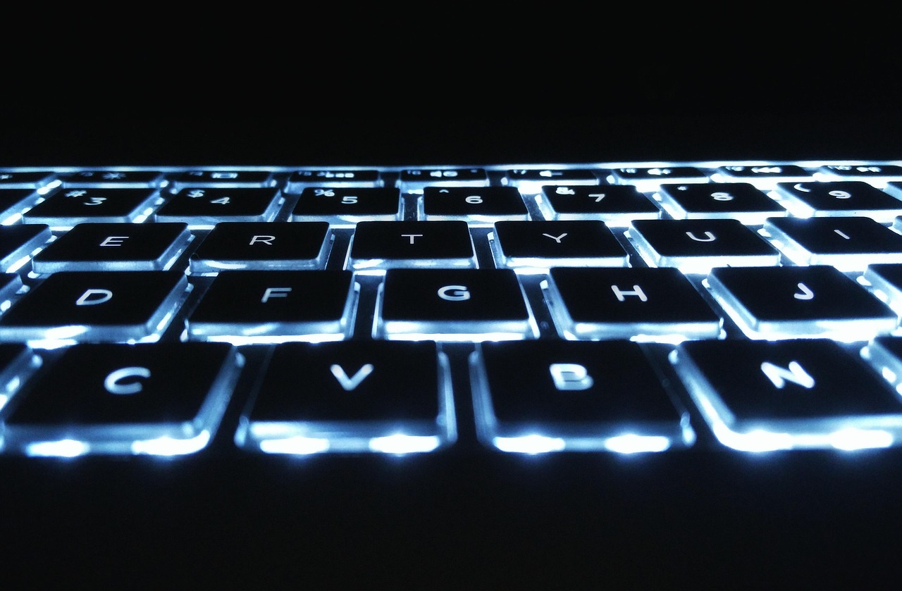 A backlit computer keyboard in the dark, the target of a keylogger
