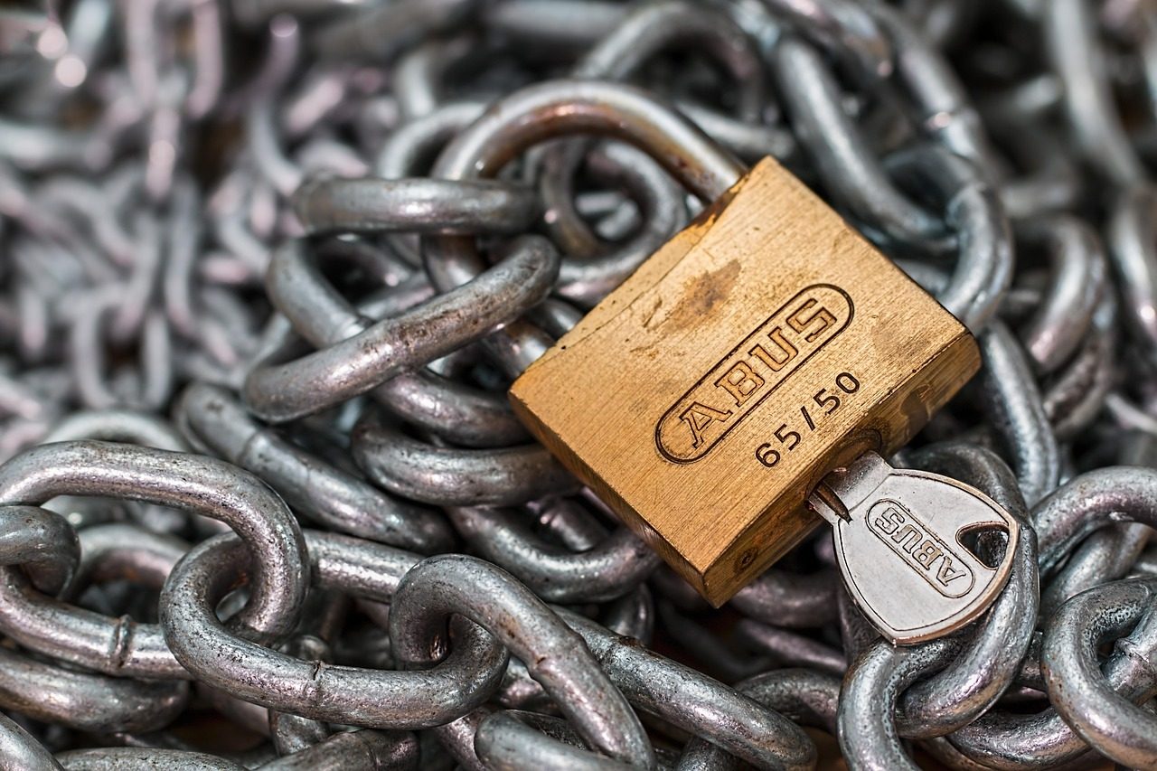 A padlock and key resting on a steel chain