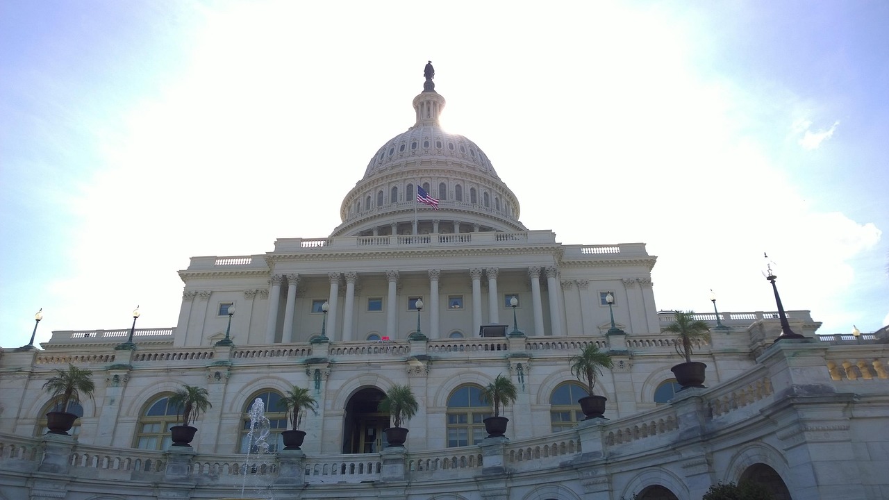 The United States Capitol in Washington, D.C., its white dome topped by a statue, with an American flag flying in front against a bright sky — federal privacy legislation has been debated here for years but not enacted as one comprehensive law, leaving the states to act.