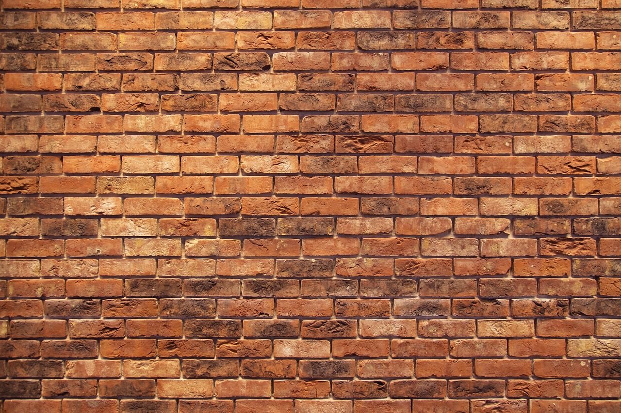 A solid red brick wall — the term "firewall" comes from a literal wall built to stop a fire spreading from one part of a building to the next.