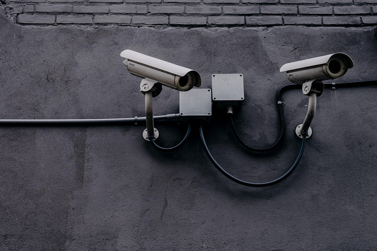 Surveillance cameras on a wall — OPSEC starts by mapping who is watching and what they can realistically collect about you.